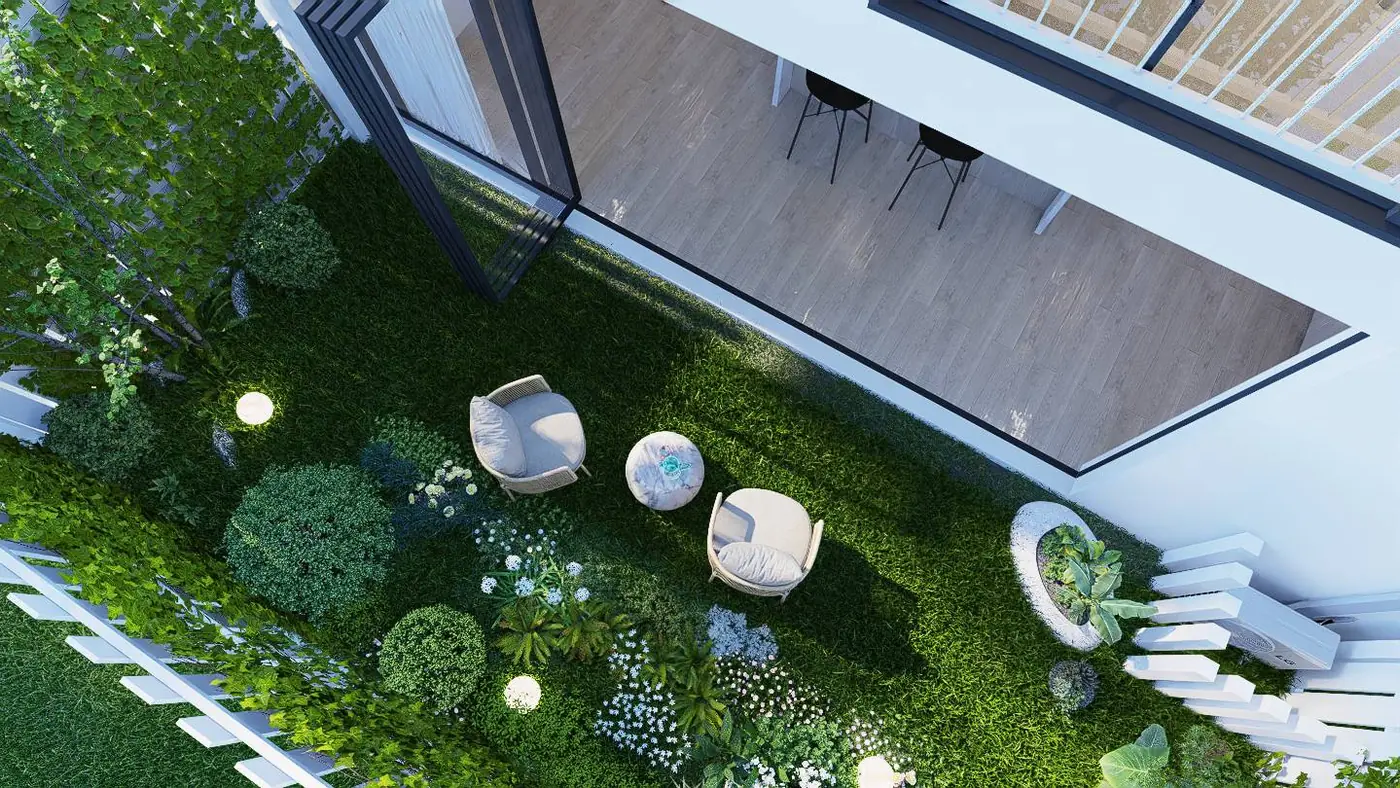 Looking down into a planted courtyard with lawn, garden beds and two lounge chairs beside the open living room.